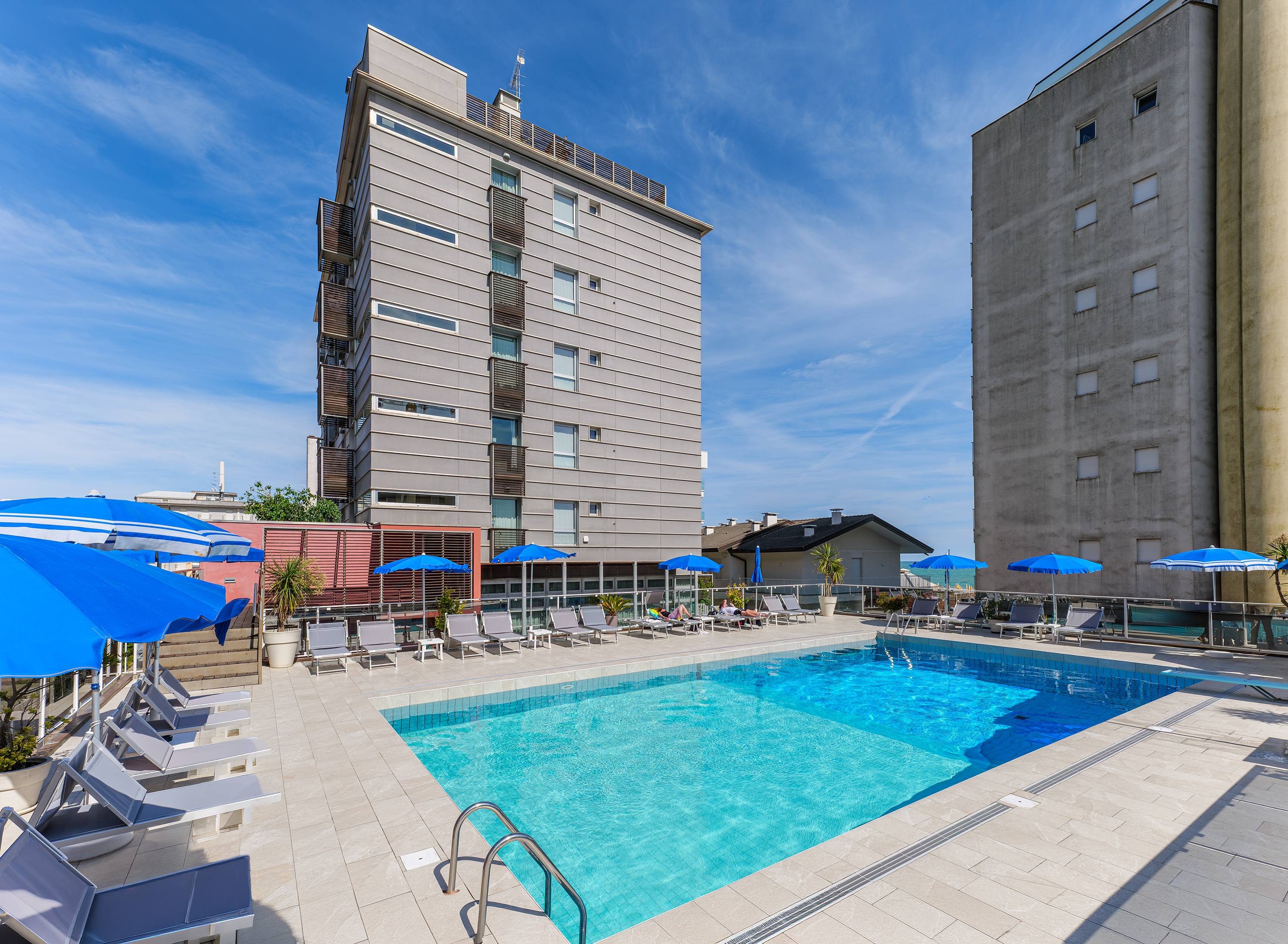 La piscina esterna dell'Hotel Rosanna a Jesolo con lettini e ombrelloni