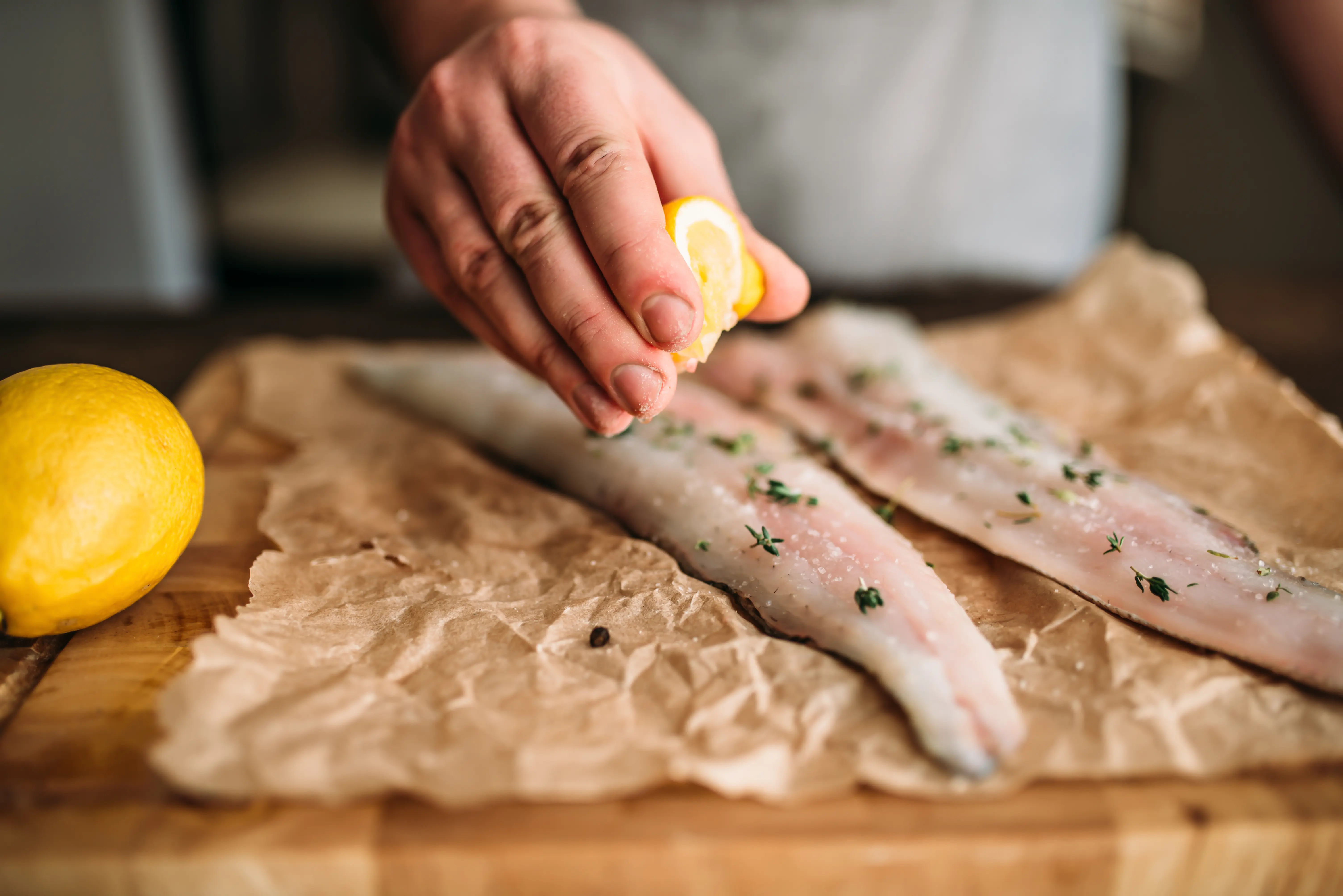 Chef che condisce filetti di pesce fresco con limone
